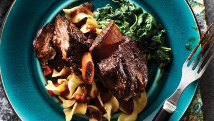 plate of fall-off-the-bone short ribs on egg noodles with sautéed spinach