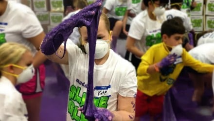One of the volunteers stretches out the purple slime between her hands