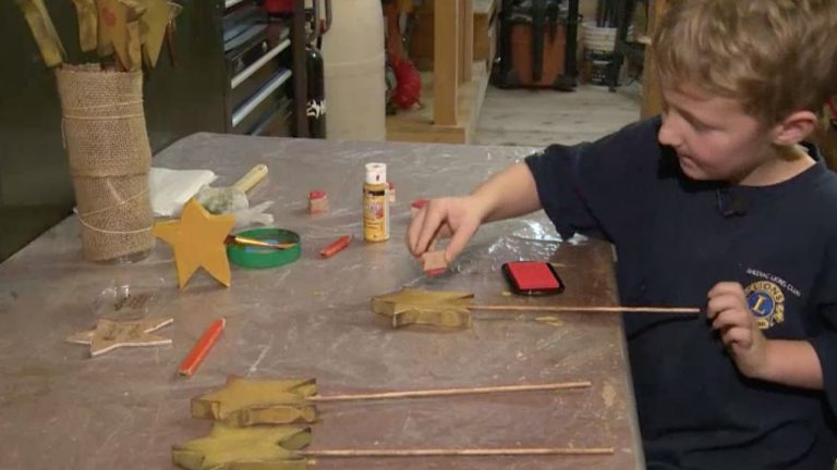 A young boy presses a heart stamp onto a hand-carved, star-shaped magic wand.