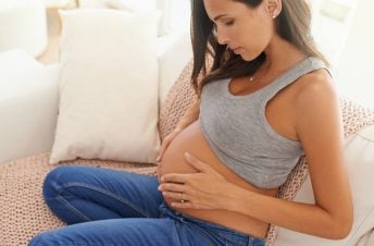 pregnant woman looking at and holding tummy