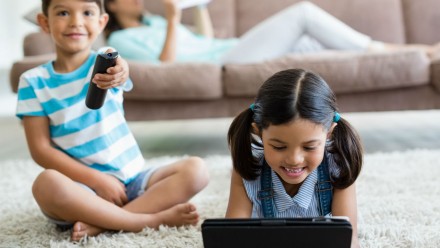 Screen addiction in kids shown by two children watching tv and a tablet