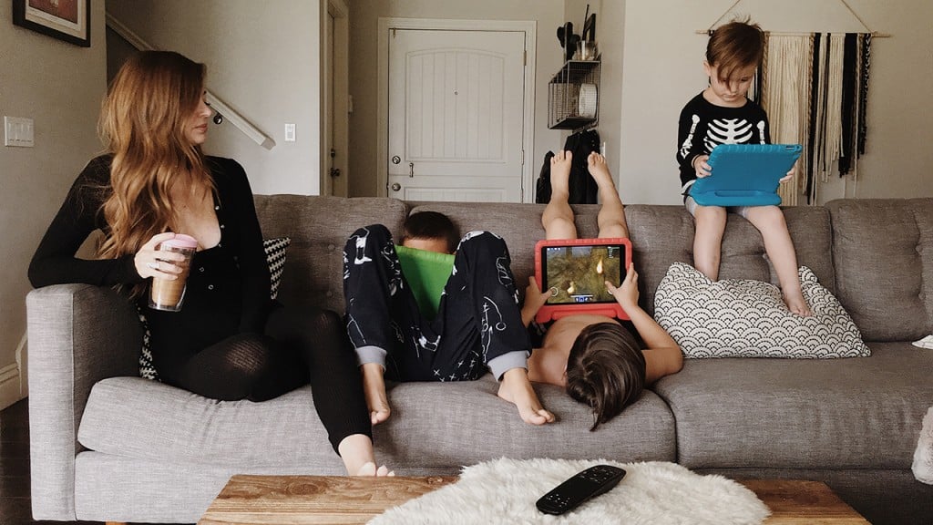 A mom surrounded by three kids on their iPads, enjoying their screen time