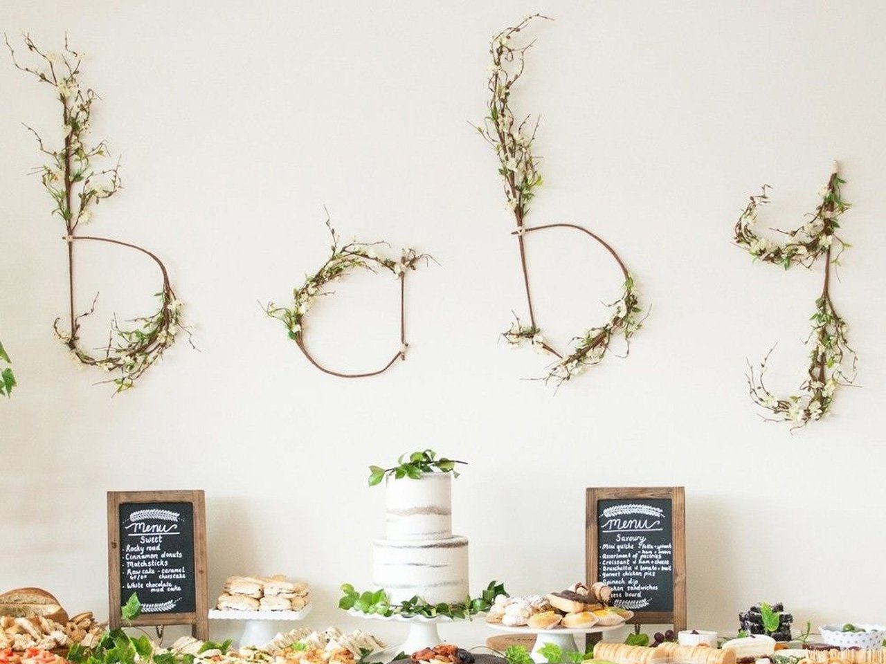 Baby spelled out in twigs with flowers and a table of food