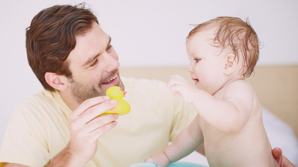 A dad holds his baby and a rubber duck