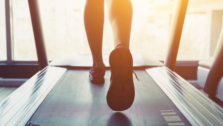 Woman running on a treadmill, showing her legs and feet only