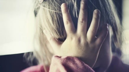 A little girl covering her face with her hands