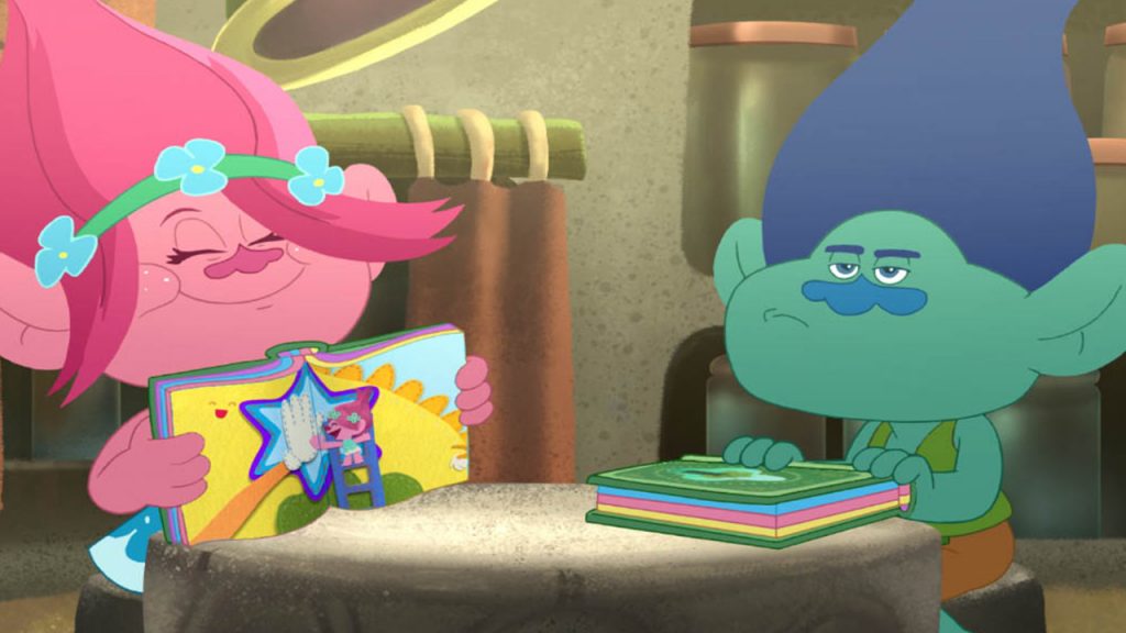 Promo image for Trolls: The beat goes on. Shows poppy and branch sitting at a table reading books.