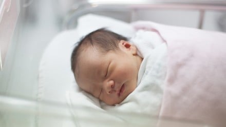 close up face of first day newborn in hospital delivery room