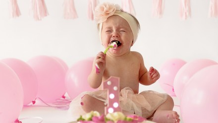 Little girl, one year old, smashing the cake during her birthday party
