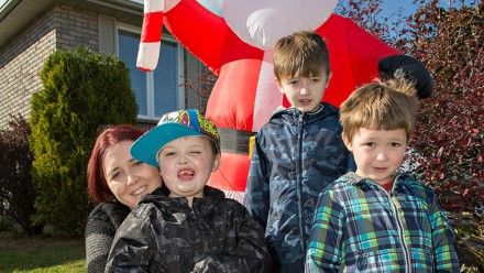 A mom and her three sons stand in front of a large inflatable Santa Claus.
