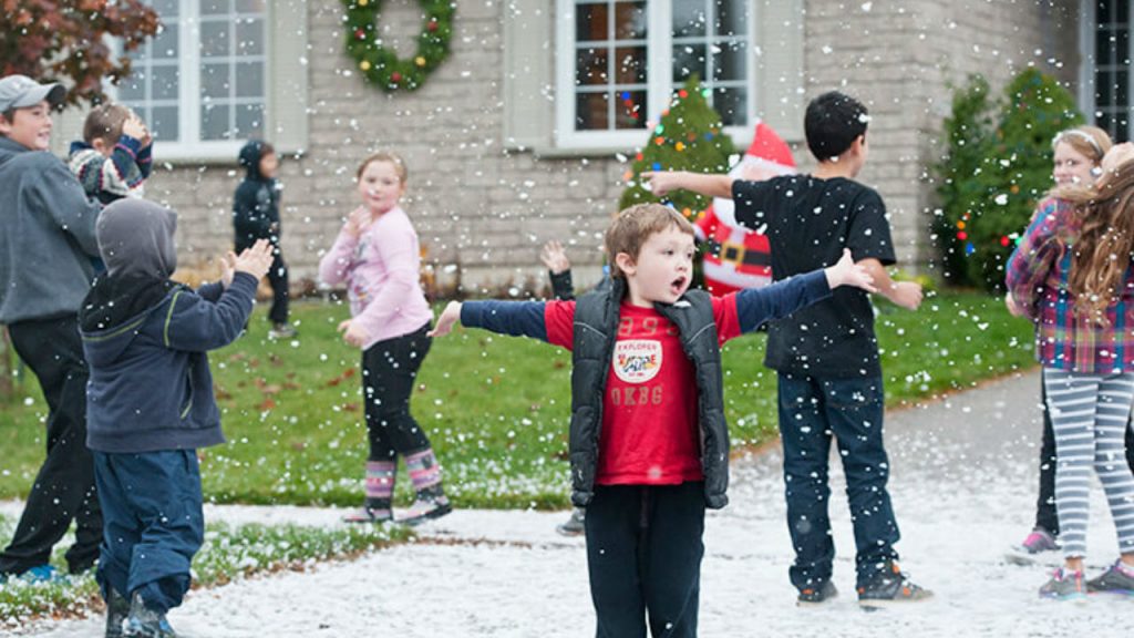 Children play outside as fake snow falls.