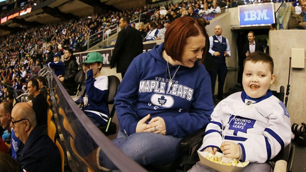 A mother and son smile for a picture in the stands of a Toronto Maple Leafs game.
