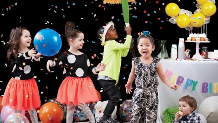 kids at a birthday party with balloons, banners and treats