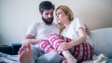 Young couple in bed looking worried