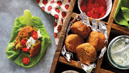 Crate with fluffy falafels, cut up tomatoes, lettuce and creamy dressing