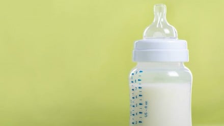 A bottle of milk on a light green background