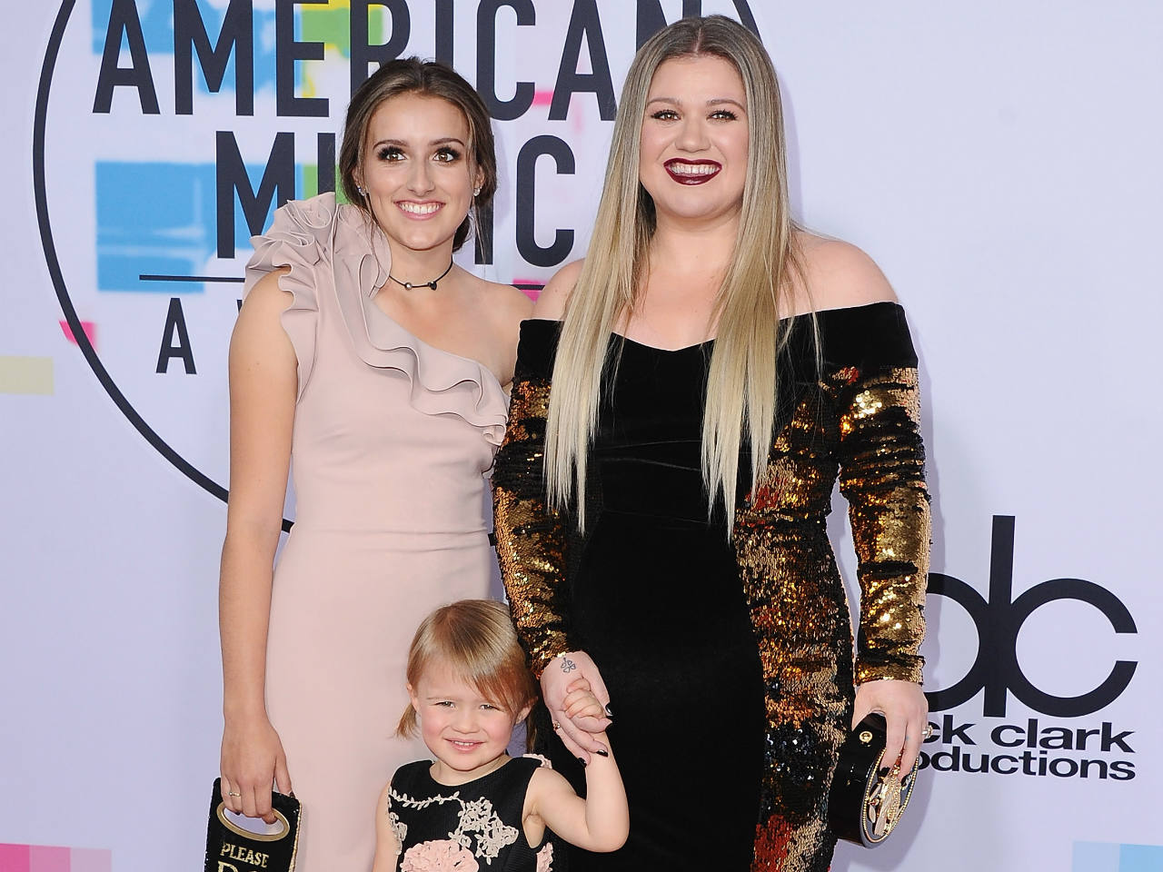 Kelly clarkson and her two daughters posing on a red carpet