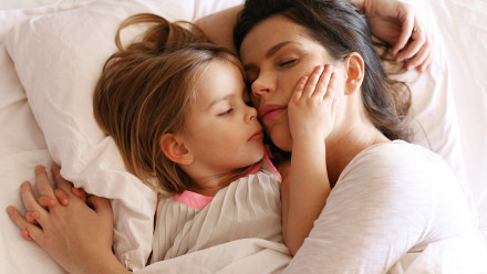 A mother tries to sleep as her young daughter grabs her face