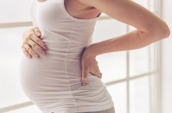 shot of a pregnant woman's belly holding her back