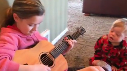 A girl plays 'You are my Sunshine' to her little brother