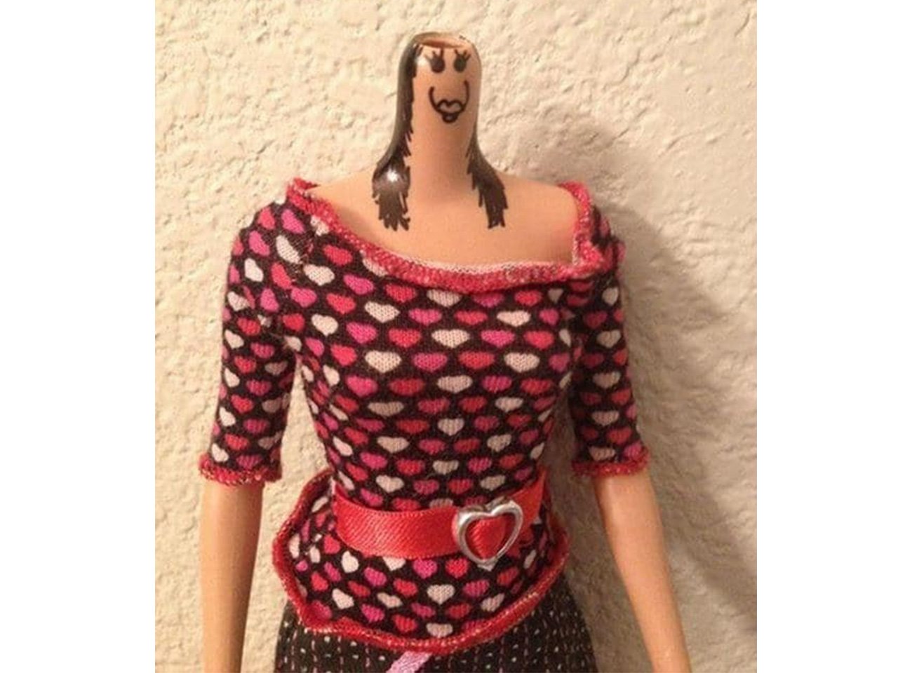 Barbie with head popped off and a creepy face drawn on neck