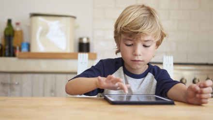 Young boy using tablet computer at kitchen table