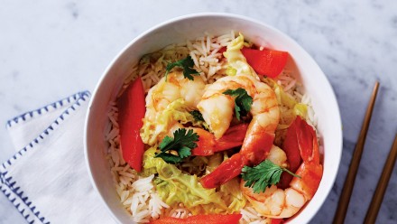 Bowl of rice topped with shrimp, red pepper, cabbage and cilantro