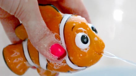 A hand squirting water out of a plastic fish toy