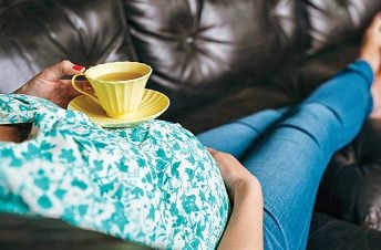 A pregnant woman lying down drinking tea