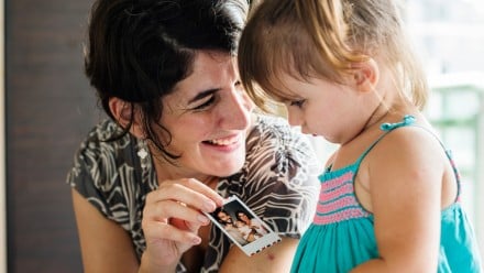 mother showing her toddler daughter snapshots from a photo album