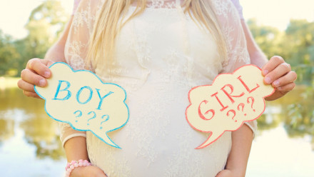 Picture of a pregnant woman's front with a sign for boy or girl on each side