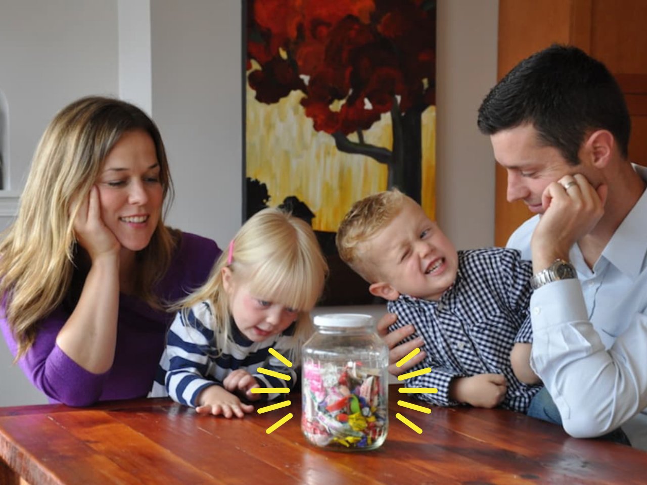 mom, dad and two kids at a table looking at a jar of garbage
