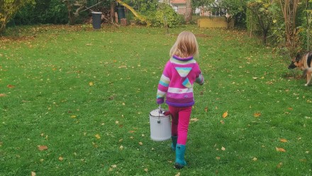 Little girl carrying a bucket to the backyard