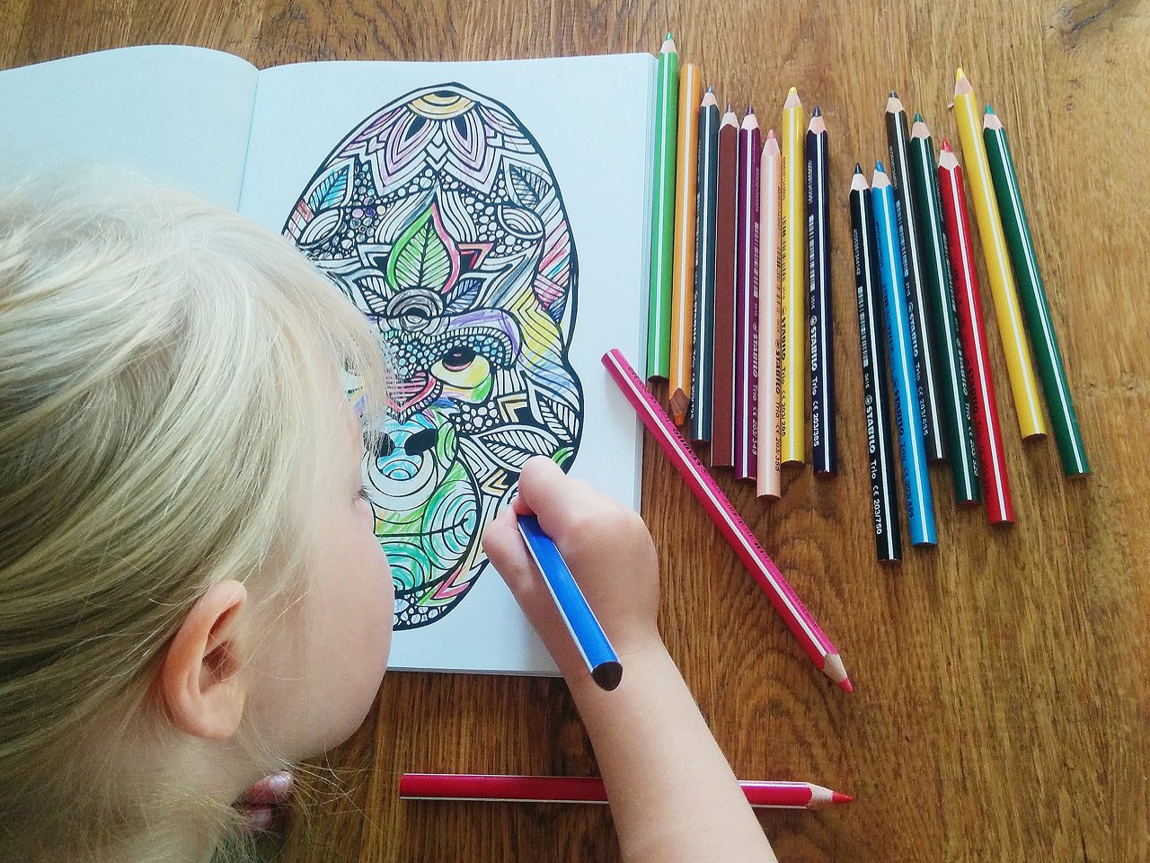 Little girl colouring a monkey in a colouring book