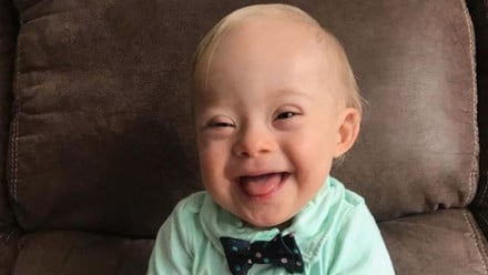 The Gerber baby smiles in a green shirt and bow tie
