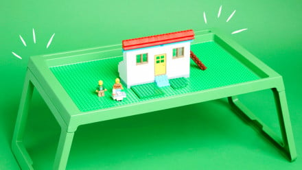 A green tray with a Lego house on top of it