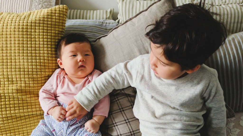 Toddler touching newborn siblings stomach