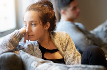 Woman looking sad on the couch beside her partner