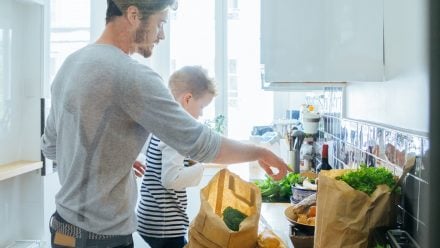 Father and son putting away groceries