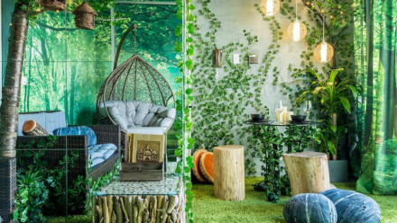 A jungle-themed room wiht a couch and hanging wicker chair
