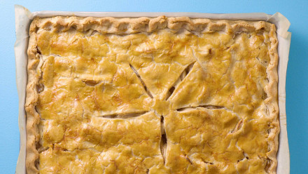 A sheet pan of apple pie on a blue background