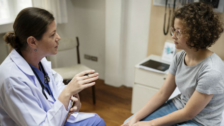 Photo of a doctor and a teen patient talking