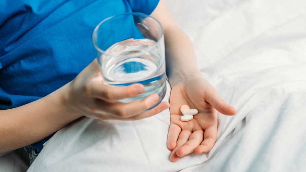 kid with a glass of water and pills in hand