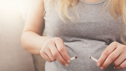 Photo of a pregnant woman's belly with a broken cigarette