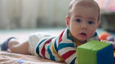 Baby enjoying tummy time activities on the floor with his toys