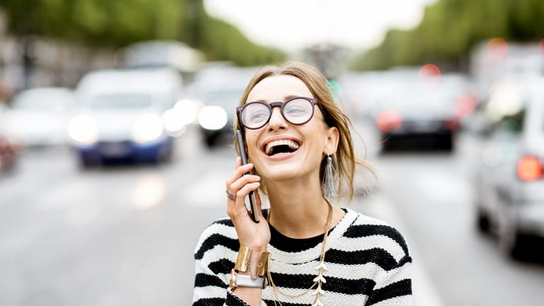 Woman laughing while on the phone in the street