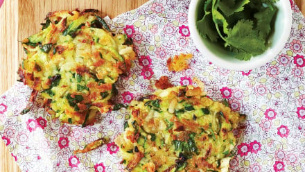 Two zucchini fritters on a floral pink napkin