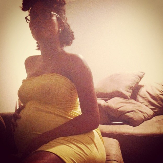 Photo of a pregnant woman in a yellow dress holding her belly