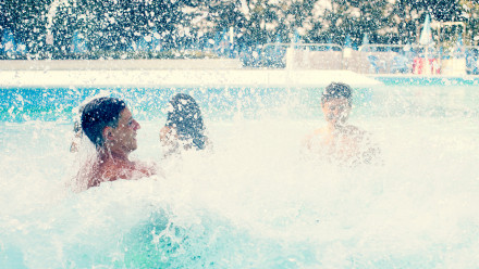 3 people splashing in a pool