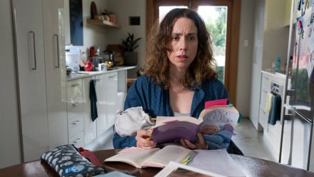 Promo image for the Letdown showing a new mom looking stressed at the table covered in baby books